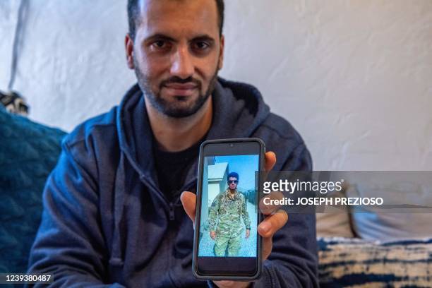 Afghani evacuee Israr shows photos on his phone of himself working in Afghanistan as a translator with military forces at his new apartment in...