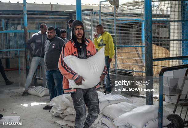 Palestinian man carries a sack of food aid from a distribution center run by the United Nations Relief and Works Agency . Food prices in Gaza City...