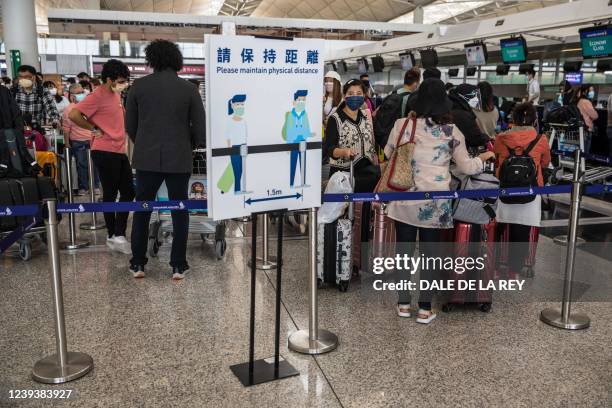 People wait in a queue to check-in for their flight at Hong Kong International Airport in Hong Kong on March 21, 2022.