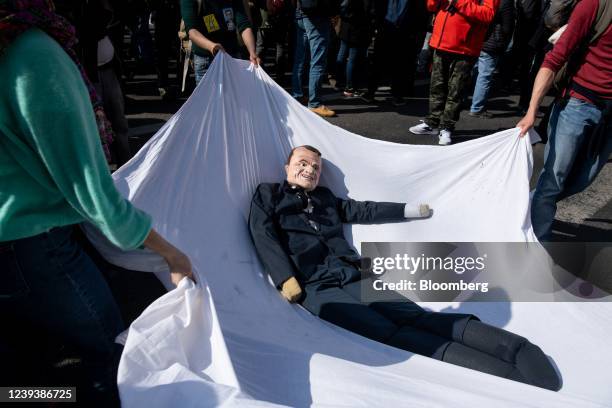 Supporters for the establishment of a Sixth Republic use a sheet to throw an effigy of France's President Emmanuel Macron into the air during a rally...