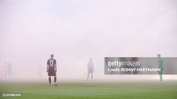 German referee Christian Dingert reacts as due to clouds of smoke the visibility on the pitch was disrupted at the start of the German first division...