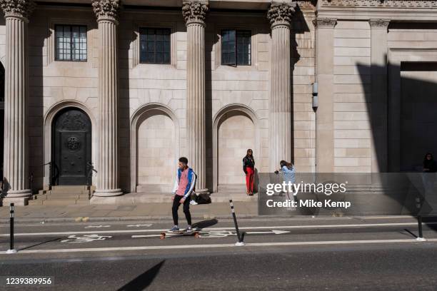 Photo shoot taking place with a woman modelling a red dress outside the Bank of England in the City of London on 18th March 2022 in London, United...
