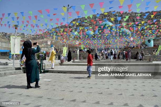 Woman uses her mobile phone to take pictures of the Karte Sakhi shrine on the first day of 'Nowruz' marking the Persian New Year in Kabul on March...