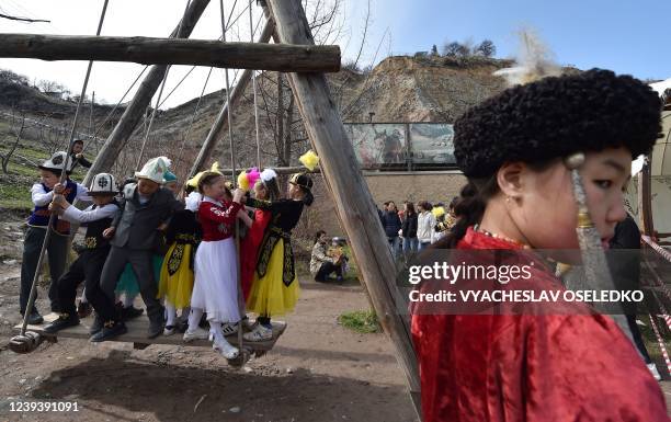 Children wearing traditional costumes play on a swing during the celebration of Nowruz in Bishkek on March 21, 2022. - Nowruz, "The New Year" in...