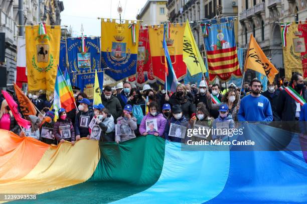 People, with a giant flag of peace and placards with images of victims of crime, during the national demonstration in Naples in memory of the...