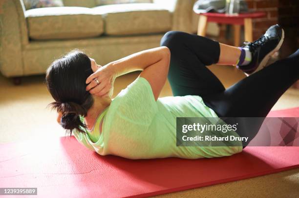 woman exercising in her living room - hiit stock pictures, royalty-free photos & images