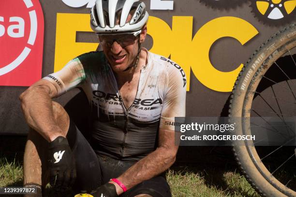 An exhausted rider sits at the finish-line after completing the first stage of the 2022 Cape Epic mountain bike stage race in the mountains above...