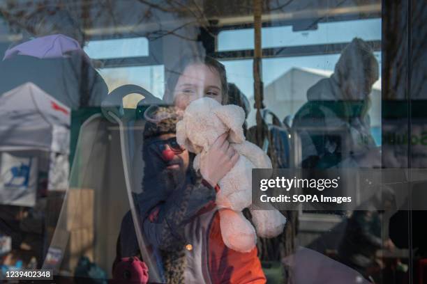 Volunteer from a disguised humanitarian organization tries to get a smile out of the girl inside a bus. People seeking refuge in Central Europe...