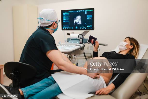 pregnant woman watching her baby on the ultrasound - prenatal care stock pictures, royalty-free photos & images