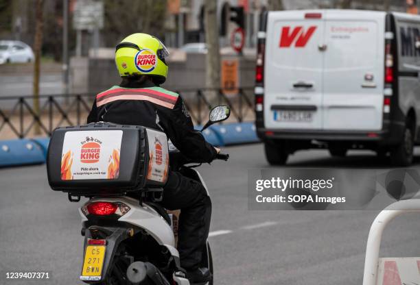 Delivery courier from the American chain of hamburger fast food restaurants Burger King rides a motorcycle in Spain.