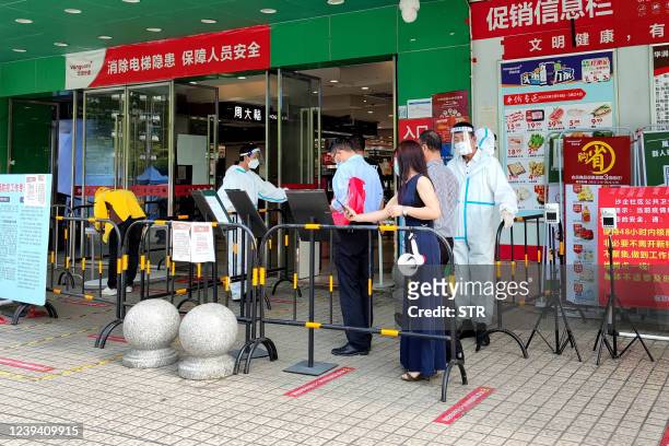 This photo taken on March 21, 2022 shows residents queueing outside a shopping mall after the city was reopened following a lockdown against a...