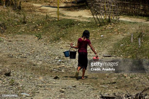 Bangladeshi woman carries water with plastic buckets as extreme water crisis in Chela Chhar village in Rangamati's Kawkhali continues to complicate...