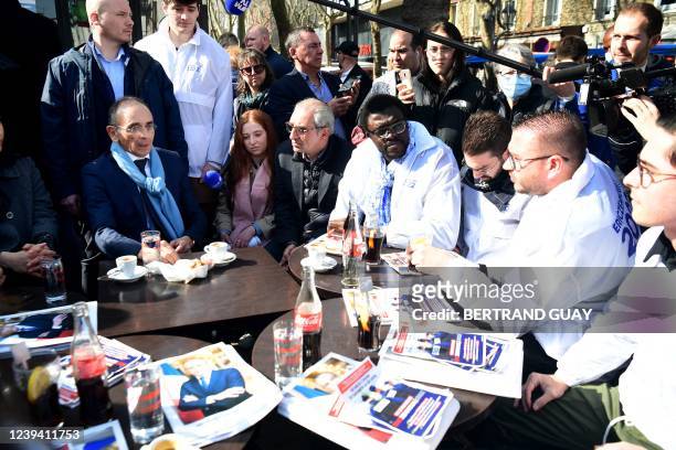 French far-right party Reconquete! presidential candidate Eric Zemmour sits for a coffee with militants while campaigning in an open air market of...