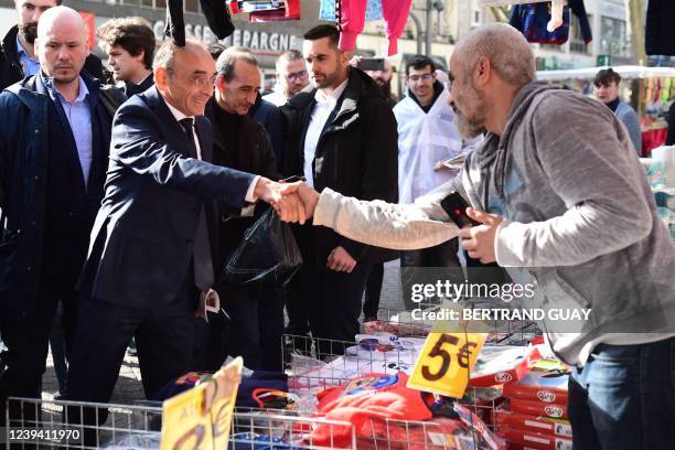 French far-right party Reconquete! presidential candidate Eric Zemmour shakes hand with a merchant while campaigning in an open air market of the...