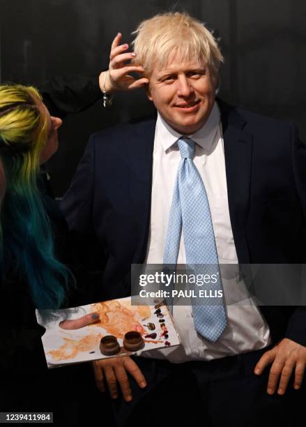 Artist Emma Meehan puts the final touches to a waxwork figure of Britain's Prime Minister Boris Johnson is pictured during a photocall for its...