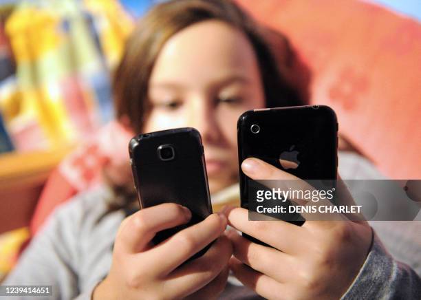 Une jeune fille envoie des SMS depuis un téléphone portable, le 08 octobre 2009. Le Sénat a interdit le 07 octobre l'usage des téléphones portables...