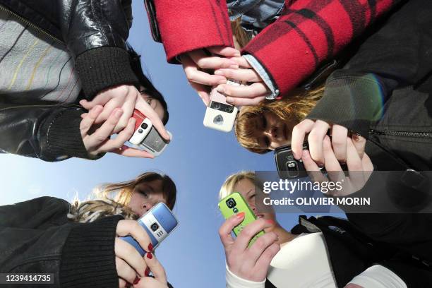 Des adolescentes utilisent leurs téléphones portables à la sortie de leur établissement scolaire à Vaasa , le 30 mars 2010. Ils s'envoient des...