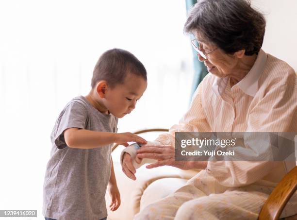grandson boy comforting his grandma's wrist fracture - wunde stock-fotos und bilder