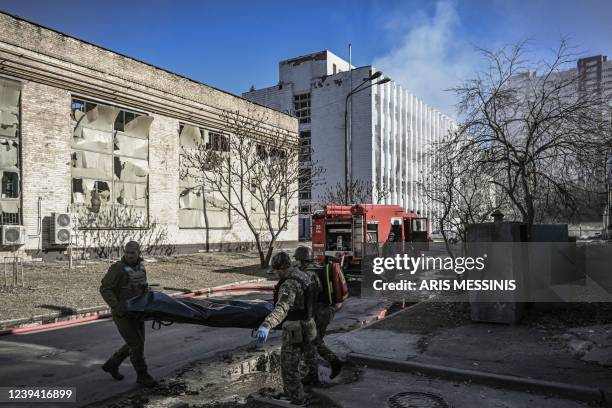 Graphic content / TOPSHOT - Military emergency service members remove the body of a dead Ukrainian serviceman in the area of a research institute,...