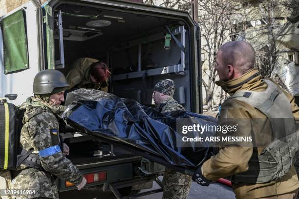 Graphic content / Military emergency service members remove the body of a dead Ukrainian serviceman in the area of a research institute, part of...