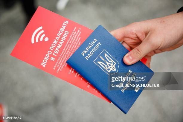 Ukrainian refugee holds a passport and a flyer for mobile phone SIM cards in his hand at the main railway station in Dresden, eastern Germany, on...