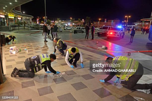 Zaka volunteers, an Ultra-Orthodox Jewish emergency response team in Israel, clean up blood stains at the scene of a knife attack outside a shopping...