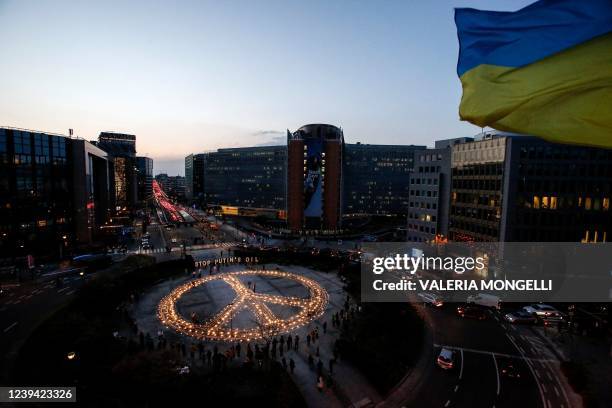 Avaaz members, demonstrators, and Ukrainian activists stand around a peace sign during a vigil for Ukraine near the European Union headquarters in...