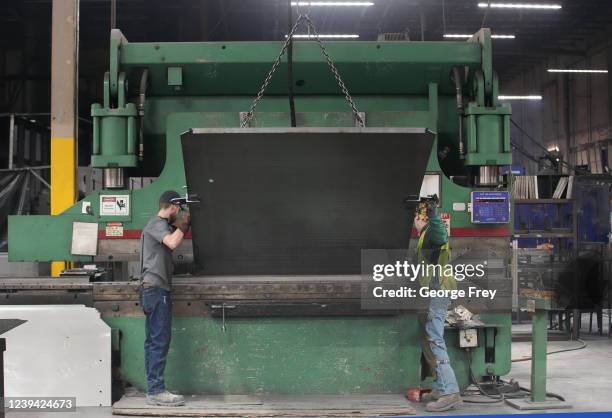 Workers feed sheet metal into a machine at Liberty Safe Company on March 22, 2022 in Payson, Utah. Liberty Safe has struggled with supply constraints...