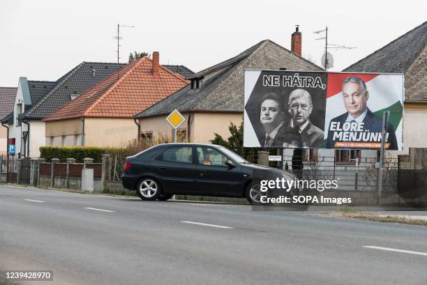 Car pass by an election billboard that displays the faces of the leader of opposition Peter Marki-Zay, former prime minister Ferenc Gyurcsany, and...
