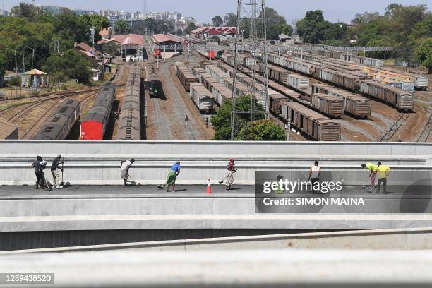 Workers sweep away loose chippings at the newly constructed Nairobi expressway along Mombasa road in Nairobi on March 23, 2022. The construction of...