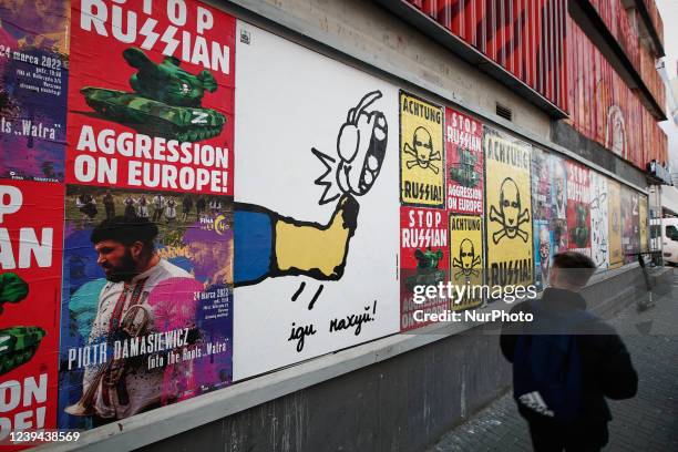 Man walks past an ant-war poster with a text in cyrillic in Warsaw, Poland on 23 March, 2022.