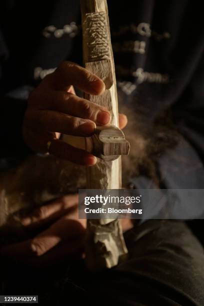 Resident holds up a carving he's working on of a dog sled team at his home in Pond Inlet, Nunavut, Canada, on Thursday, Nov. 11, 2021. Across the...