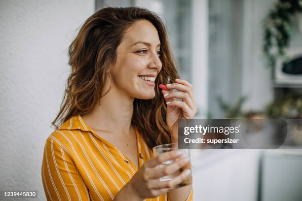 junge erwachsene nimmt ergänzungen zu hause - nahrungsergänzungsmittel stock-fotos und bilder