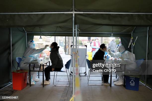 Medical staff take nucleic acid samples for residents at a nucleic acid sampling site in Qingdao, Shandong Province, China, March 23, 2022.