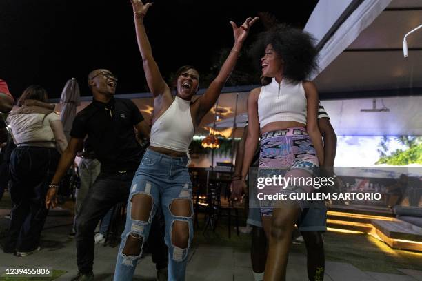 Woman raises her hands as others dance near her in a nightclub during an amapiano party in Johannesburg, on February 26, 2022. - On a viral video of...