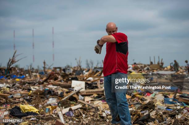 Titus Neuenschwander, of Joplin, Mo., wipes sweat from his face while picking up keepsakes from the tornado debris at his father-in law, Travis...