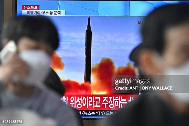People sit near a television showing a news broadcast with file footage of a North Korean missile test, at a railway station in Seoul on March 24,...