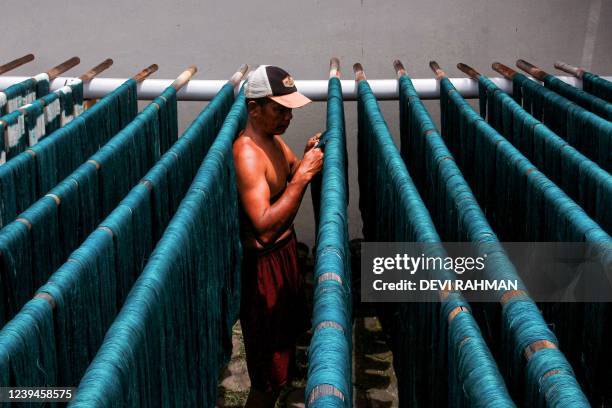 Man handles dyed yarn before being woven into cloth at a traditional textile factory in Yogyakarta on March 24, 2022.