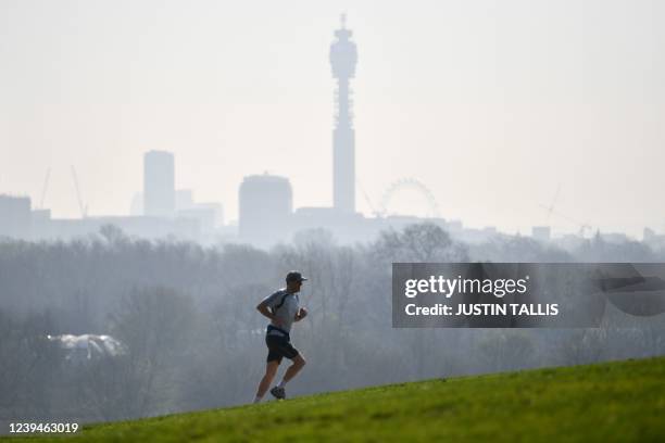 Runner jogs at Primrose Hill with the BT Tower and the London Eye in the background as a high air pollution warning was issued for London on March...