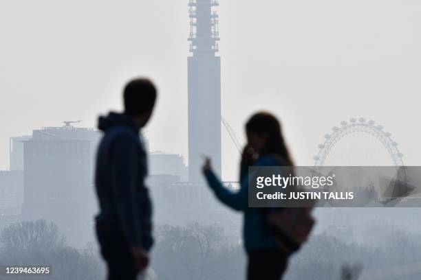 Two people visiting Primrose Hill look towards the BT Tower and the London Eye as a high air pollution warning was issued for London on March 24,...