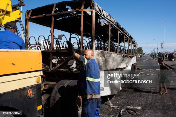 Employees of the Golden Arrow Bus Company prepare to tow a bus that was set on fire during a strike by taxi associations, in Nyanga, near Cape Town,...