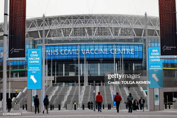 People arrive at the newly-set up Wembley Stadium vaccination centre to receive their the Covid-19 vaccine or booster in London on December 19 as the...