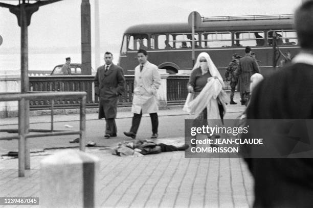 People pass by a dead demonstrator, after a pro-independence demonstration on December 11, 1960 during which Algerian Muslims marched on the center...