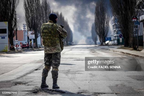 Ukrainien serviceman stand guard near a burning warehouse hit by a Russian shell in the suburbs of kyiv, on March 24, 2022