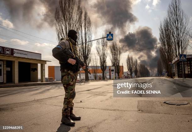 Ukrainien serviceman stands guard near a burning warehouse hit by a Russian shell in the suburbs of the capital Kyiv on March 24, 2022. - The UN...