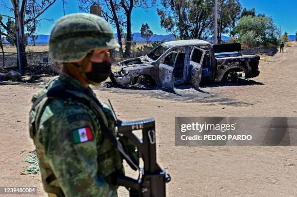 Mexican soldier stands guard next to a burnt house in the village of Palmas Altas, which had been taken over by criminal gangs and its residents had...