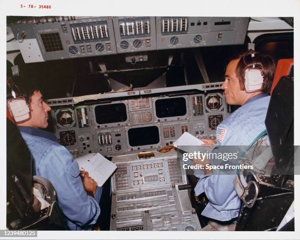 Astronaut John W Young, crew commander, and Robert L Crippen, pilot, go over a checklist in the Space Shuttle mission simulator in the mission...