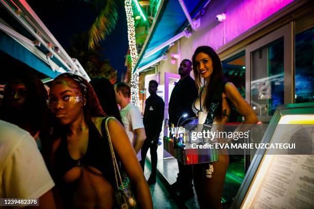 People walk past to a cigar vendor on Ocean Drive during Spring Break in Miami Beach, Florida, on March 24, 2022. - The US city of Miami Beach has...