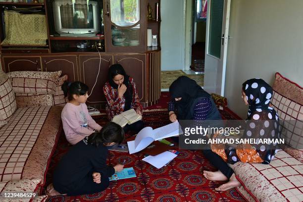In this photograph taken on March 24 school girls Malahat Haidari and her sister Adeeba Haidari study at their home with their younger sisters and...