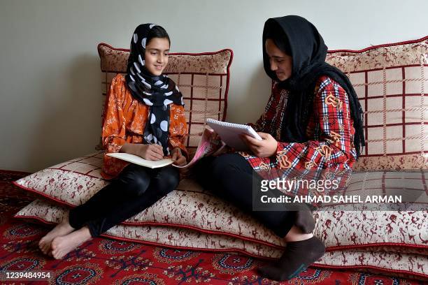 In this photograph taken on March 24 school girls Malahat Haidari and her sister Adeeba Haidari study at their home in Kabul. - Days after the...